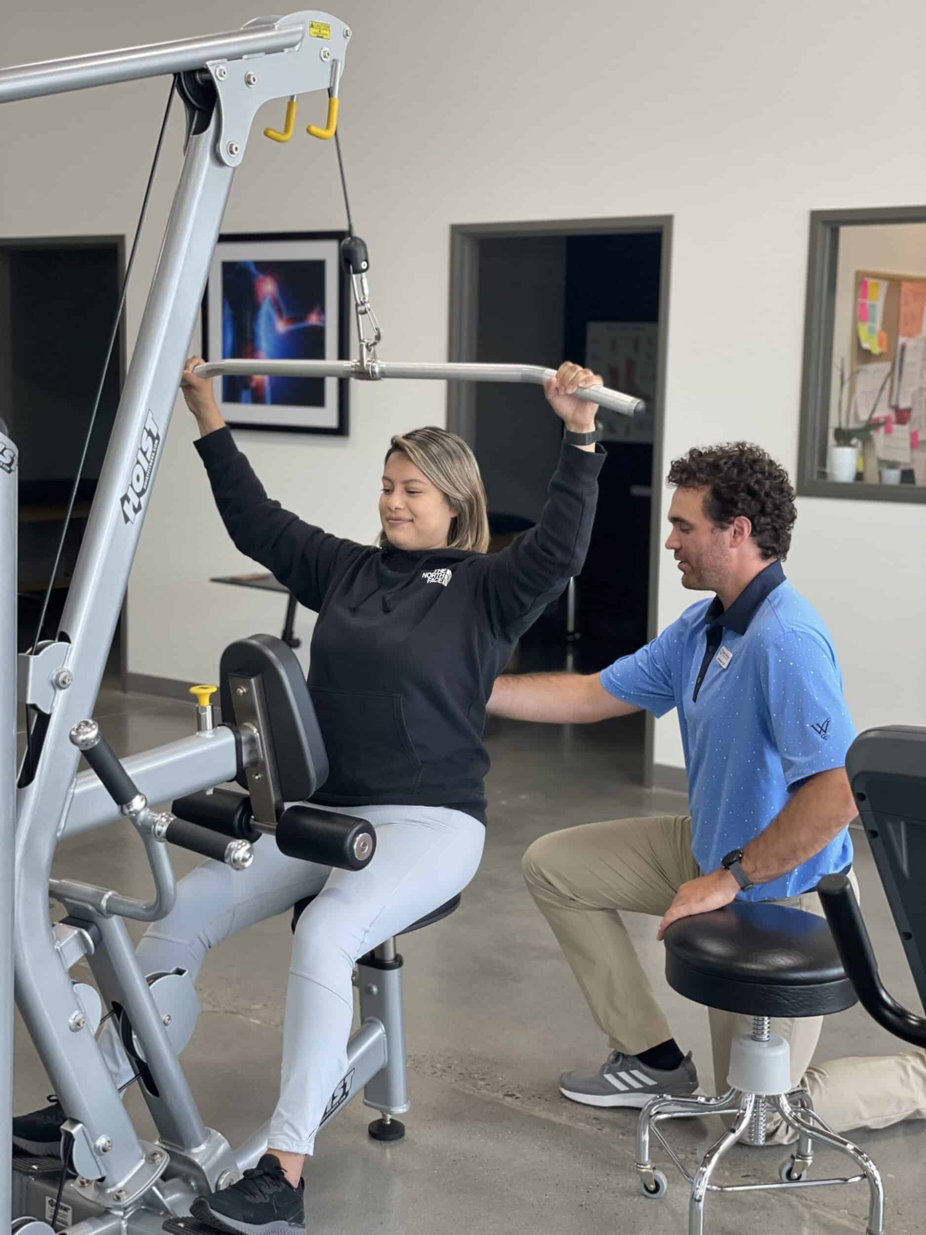 woman undergoing physical therapy on weight pull-down machine