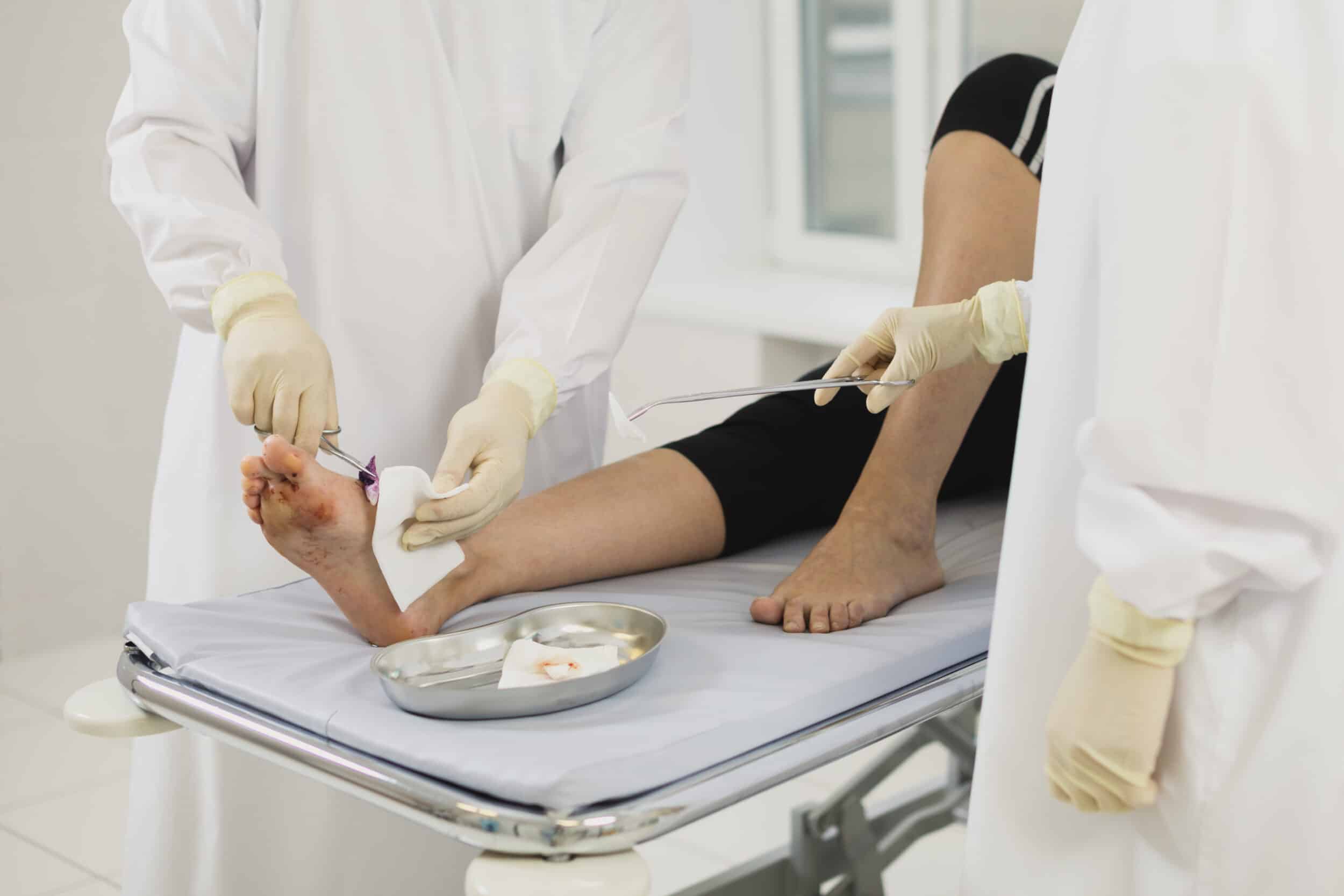 A doctor treating a laceration on a patient’s leg
