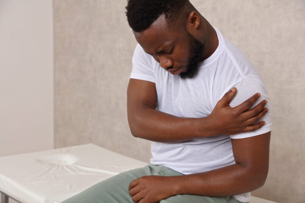 Young man with dislocation clutches his shoulder in pain